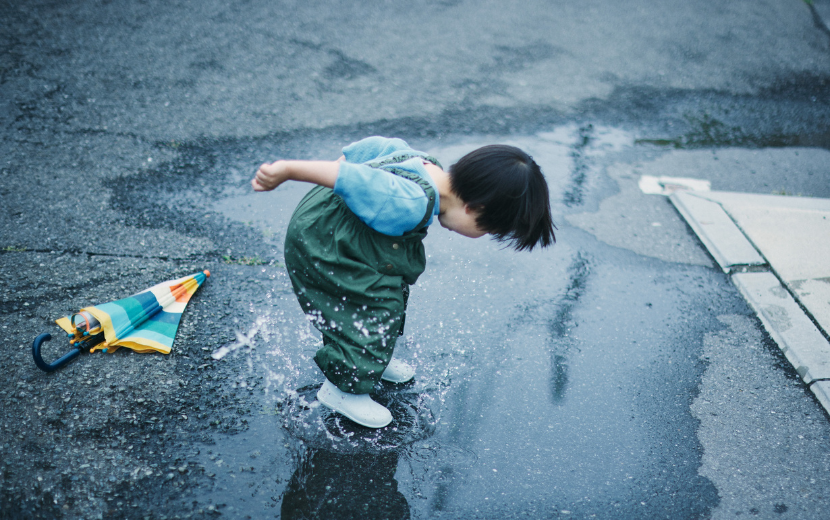 雨上がりの公園で水たまりで遊ぶ子ども